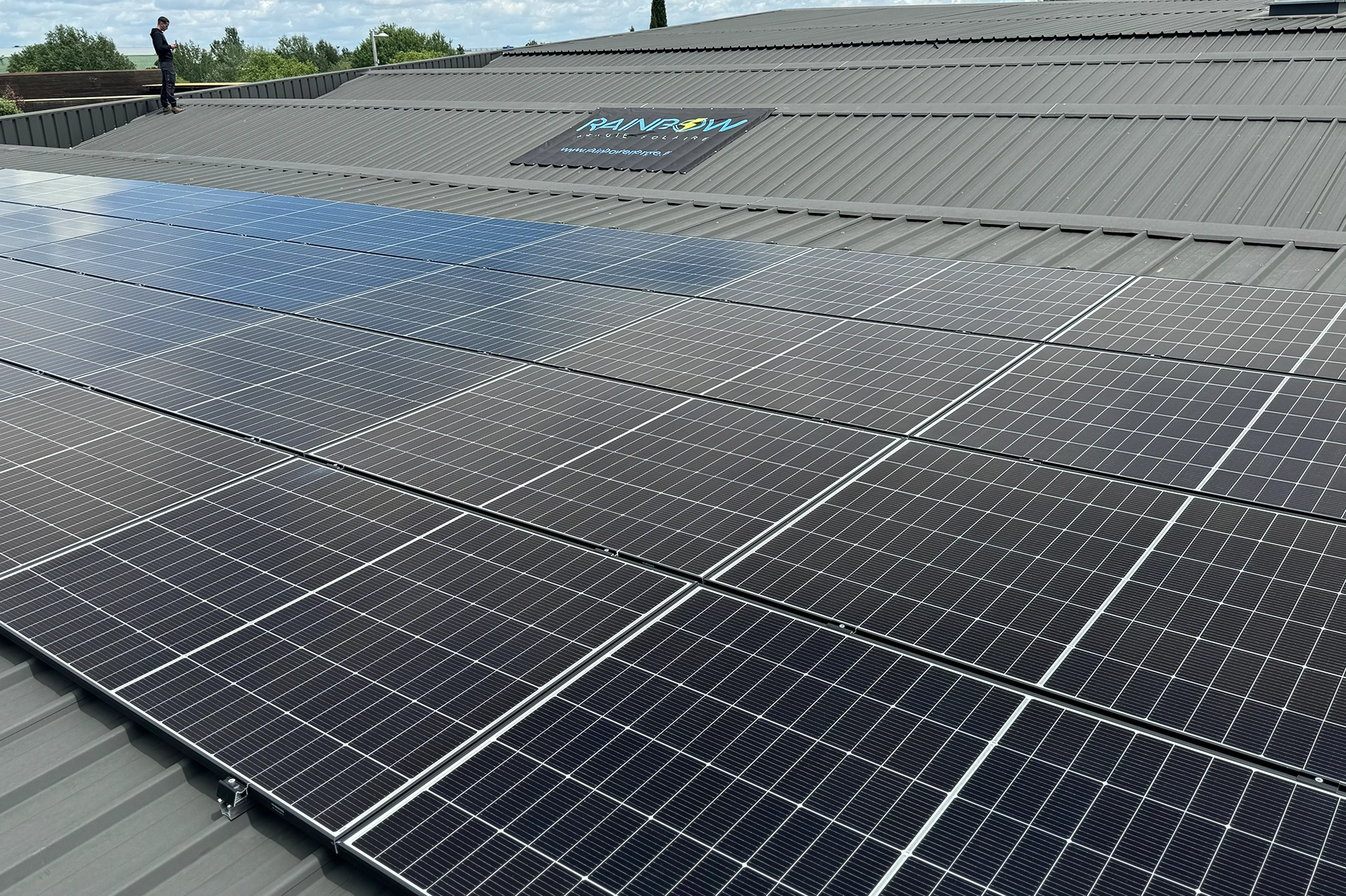 toit entreprise avec panneaux solaires et logo rainbow énergie